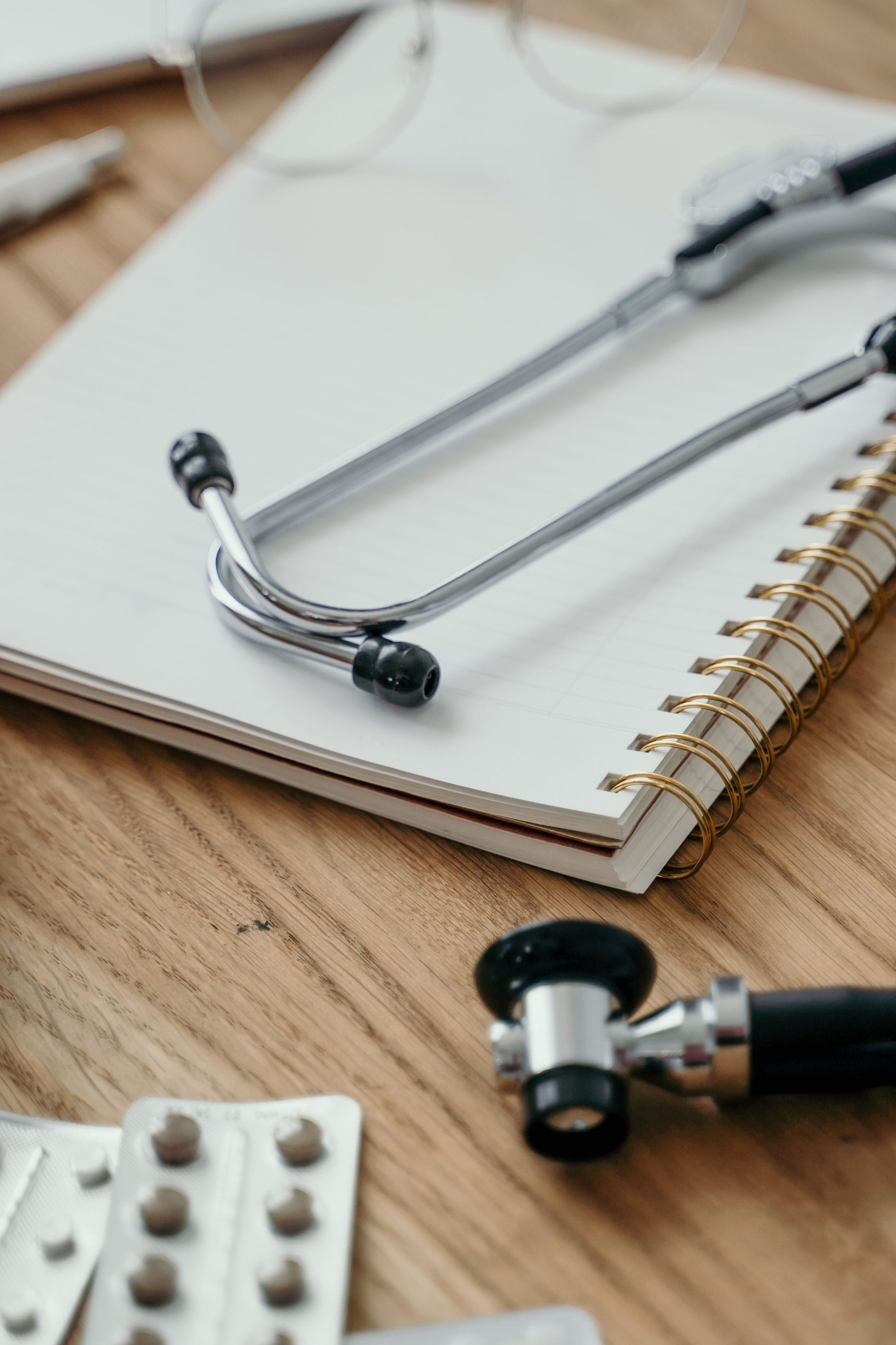A clinician's stethoscope resting on a notebook